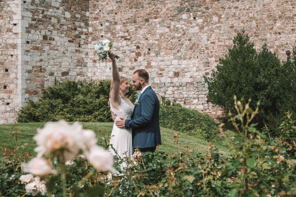 Poročna fotografija mladoporočencev; ujet pristen trenutek z naravno svetlobo in umirjeno kompozicijo v dokumentarnem slogu.